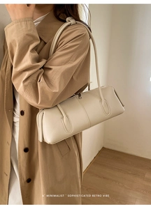 Detail shot of cream-colored tote with fine litchi texture on a model in a trench coat