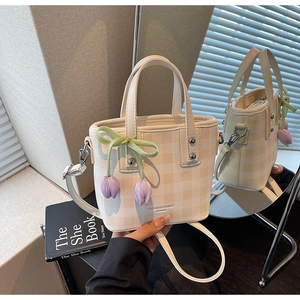 Détail du mini sac seau à carreaux crème avec breloques tulipes et nœud vert