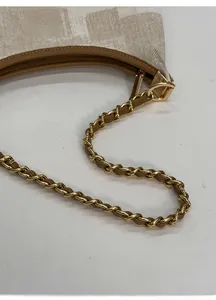 Gros plan détaillé du sac bandoulière en toile beige avec bordure en cuir marron et chaîne