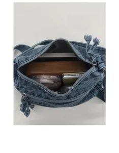 Macro view of blue denim crossbody bag interior showing spacious compartments and storage