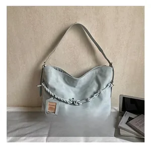 Close-up of light blue shoulder bag featuring woven chain detail and sleek leather texture