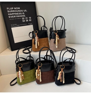 Detail of five mini bucket bags with suede stitching, bead charms, and double handles