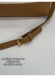 Détail macro de la bandoulière réglable en cuir marron avec boucle dorée et couture