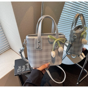 Détail du mini sac seau argenté à carreaux avec ruban vert et breloque fleur de tulipe