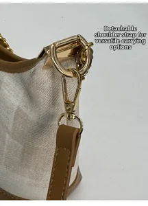 Détail de la bandoulière amovible avec boucle dorée sur un sac cabas en cuir beige