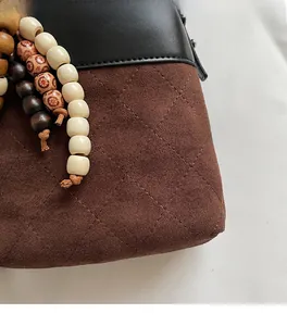 Macro shot of brown frosted suede texture and beaded tassel detail on bucket bag