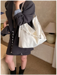 Detail of a large white PU leather tote bag with a unique woven knot strap on the shoulder
