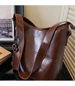 Detail of vintage brown bucket bag with wax leather texture and side logo stamp