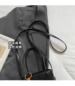 Detail of black leather bucket bag with vintage gold metal rings on a grey suit jacket