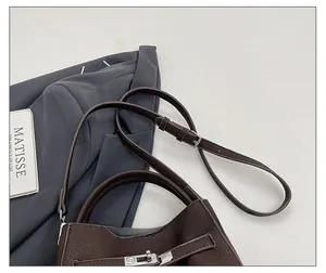Detail of dark brown pebble leather handbag featuring silver twist lock and handle