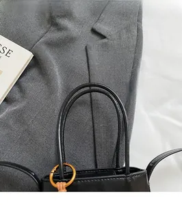 Detail of round handles and gold metal hardware on black faux leather bucket bag