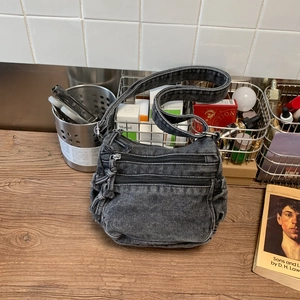Detail shot of black denim crossbody bag with dual zipper pockets and retro washed finish