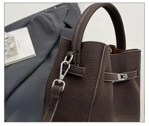 Detail of dark brown leather bucket bag showing lychee grain texture and silver hardware