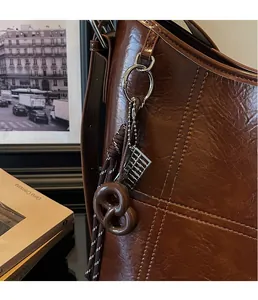 Close-up of vintage brown leather bucket bag with creative pendant and mini silver abacus