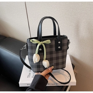 Détail d'un mini sac cabas à carreaux gris avec ruban vert et breloques de tulipes