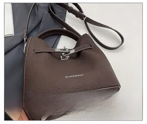 Detail of dark brown lychee leather bucket bag with silver metal swivel lock and logo