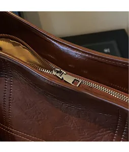 Close-up of shiny silver metal zipper on premium brown vintage leather bucket bag