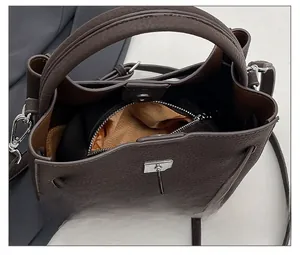 Detail view of brown pebbled leather bucket bag with magnetic closure and key charm