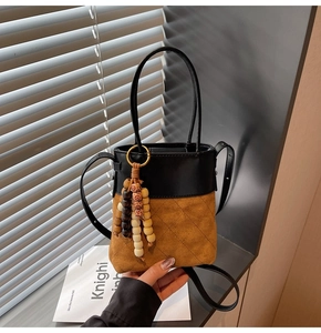Detail of vintage bucket bag featuring quilted suede texture and wooden bead charm