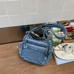 Detail of vintage blue denim bag with multi-layer zippers and washed texture design