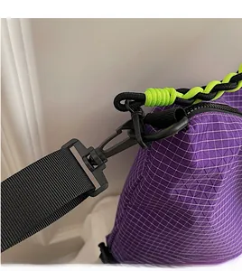 Detail of purple plaid crossbody bag featuring durable black hooks and neon rope accents