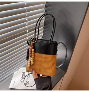 Close-up of dual-tone bucket bag featuring quilted suede and decorative wood beads