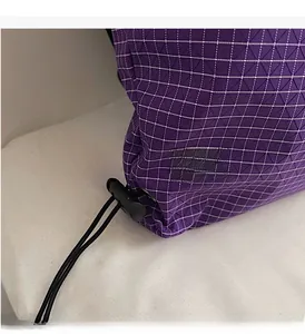 Detail of purple plaid nylon fabric with black elastic drawstring and plastic toggle