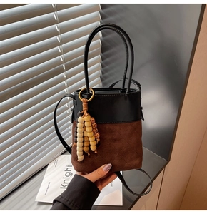 Detail of vintage patchwork bucket bag with suede texture and wooden bead tassel charm