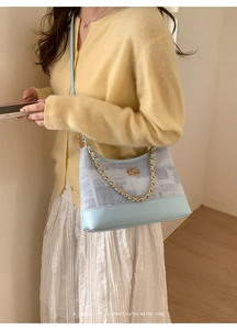 Détail du sac patchwork en denim bleu clair et cuir avec chaîne dorée et logo