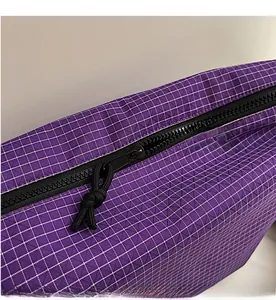 Detail of smooth black zipper closure on a purple checkered nylon tote bag