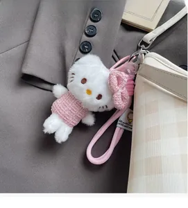 Détail du pendentif Hello Kitty en peluche avec robe en tweed sur un sac seau à carreaux