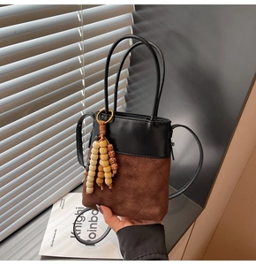 Detail view of vintage bucket bag with diamond-quilted suede and wooden bead tassels