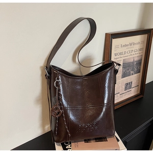 Macro detail of dark brown oiled leather texture and embossed logo on the bucket bag