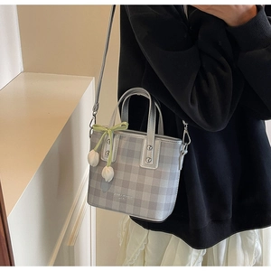 Vue détaillée du sac seau à carreaux gris avec breloques fleurs 3D et ruban vert