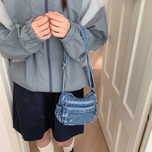Detail view of the vintage denim crossbody bag with dual zipper pockets and side drawstrings