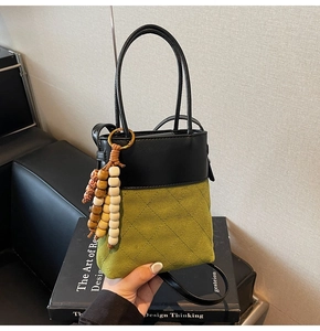 Detail of suede patchwork bucket bag with colorful wooden bead tassel accessory