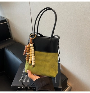 Detail of bicolored bucket bag with quilted olive suede and decorative wooden beads