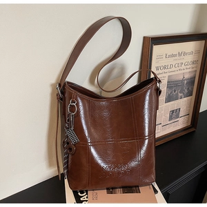 Detail of vintage dark brown bucket bag showing glossy leather texture and embossed logo