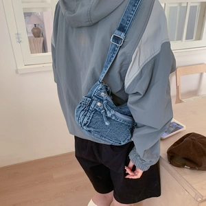 Detail of adjustable metal buckle on blue denim shoulder bag with utility pockets