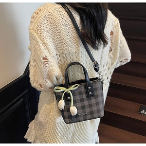 Détail du sac seau à carreaux gris avec nœud jaune et pendentifs tulipes