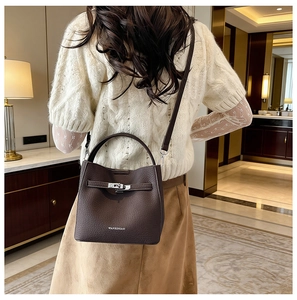 Detail of dark brown pebble leather bucket bag with silver turn-lock and brand logo