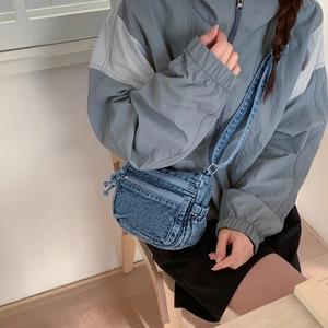 Detailed view of casual blue denim crossbody bag with vintage washed finish and zippers