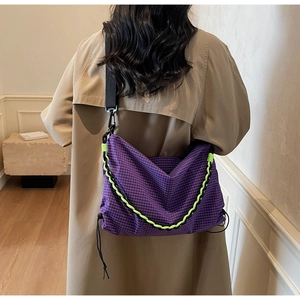 Detail of purple plaid crossbody bag featuring bright green braided rope and adjustable strap