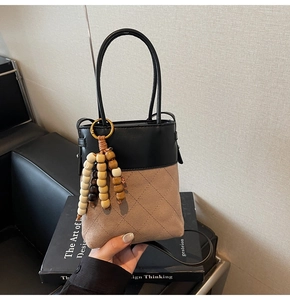 Detail of color-block bucket bag featuring quilted suede and wooden bead ornament