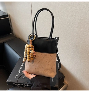 Detail of suede bucket bag with contrast leather stitching and colorful beaded charms