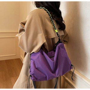 Detail of purple checkered tote bag with neon green woven strap and drawstring side closure