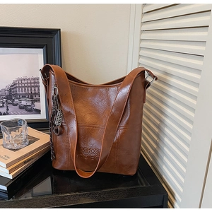 Detailed view of the brown bucket bag's embossed texture and braided knot charm