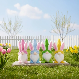 Lot de quatre nains de Pâques colorés avec de longues oreilles sur une pelouse de jardin