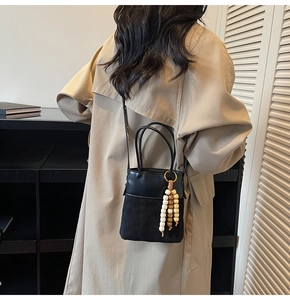Detail of black suede and leather bucket bag with decorative wooden bead charms