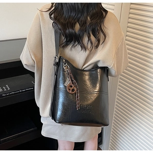 Close-up of black Hobo bag with embossed logo, textured finish and creative heart charms